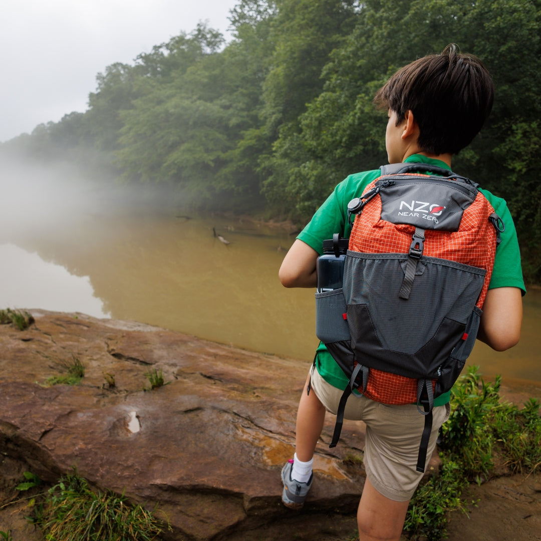 Near Zero Outdoor Gear - Little Dean - 20L Hiking Backpack - Young person posing with backpack by a lake