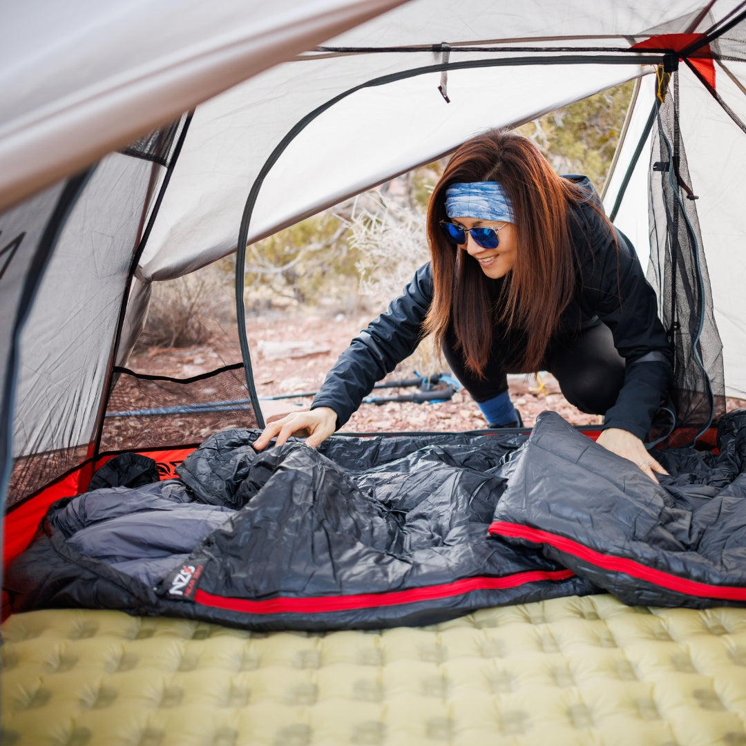 Near Zero Outdoor Gear - Peralta 25 Synthetic Sleeping Bag - Woman laying out a sleeping bag on a pad inside a tent