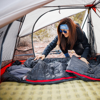 Near Zero Outdoor Gear - Peralta 25 Synthetic Sleeping Bag - Woman laying out a sleeping bag on a pad inside a tent