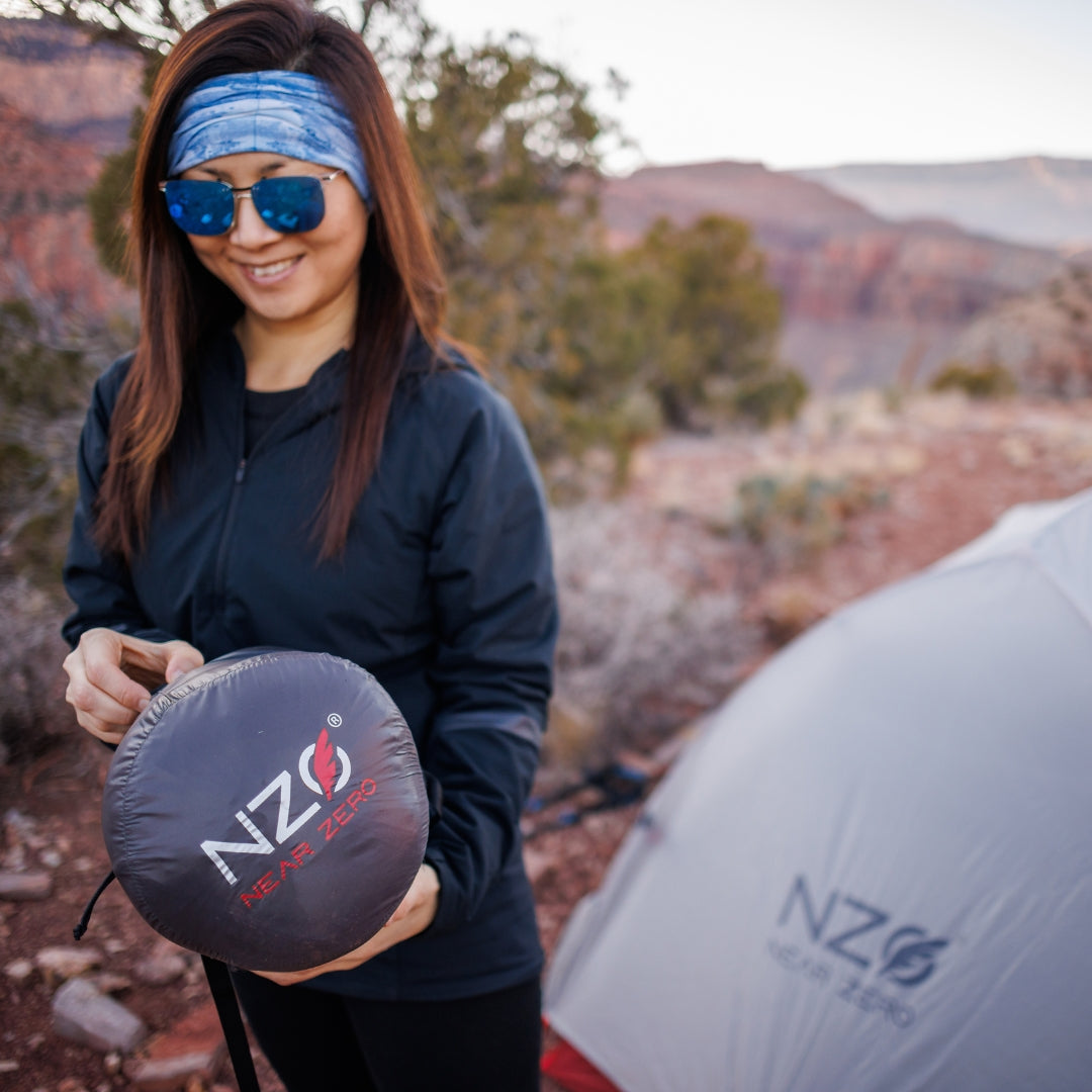 Near Zero Outdoor Gear - Peralta 25 Synthetic Sleeping Bag - Woman holding a sleeping bag rolled up in a stuff sack