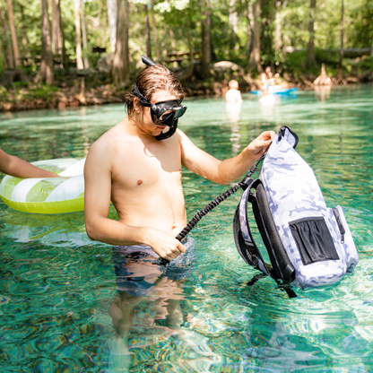 Dry Pocket - Waterproof Floating Backpack Dry Bag - Snow Camo - Man wearing snorkel mask, using bag in water
