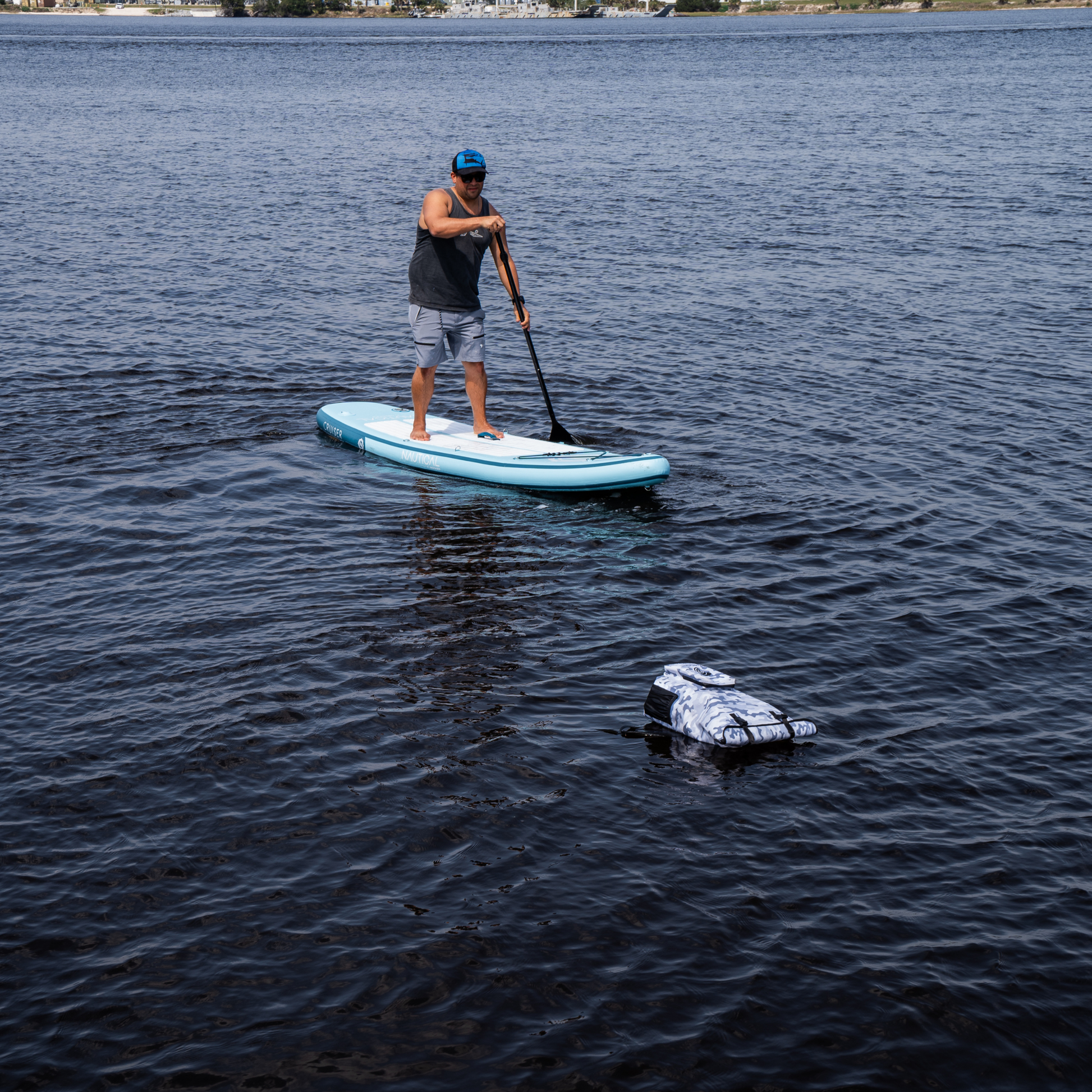 Dry Pocket - Waterproof Floating Backpack Dry Bag - Snow Camo - Floating in water in front of paddleboarder