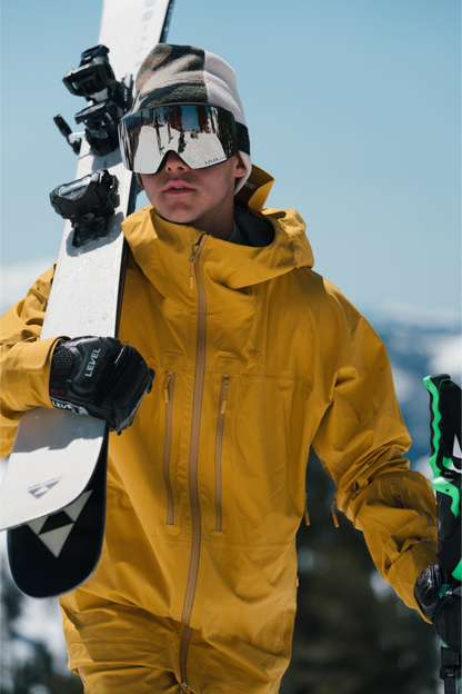 Strafe Outerwear - Pyramid Jacket - Standing with a snowboard - Dijon