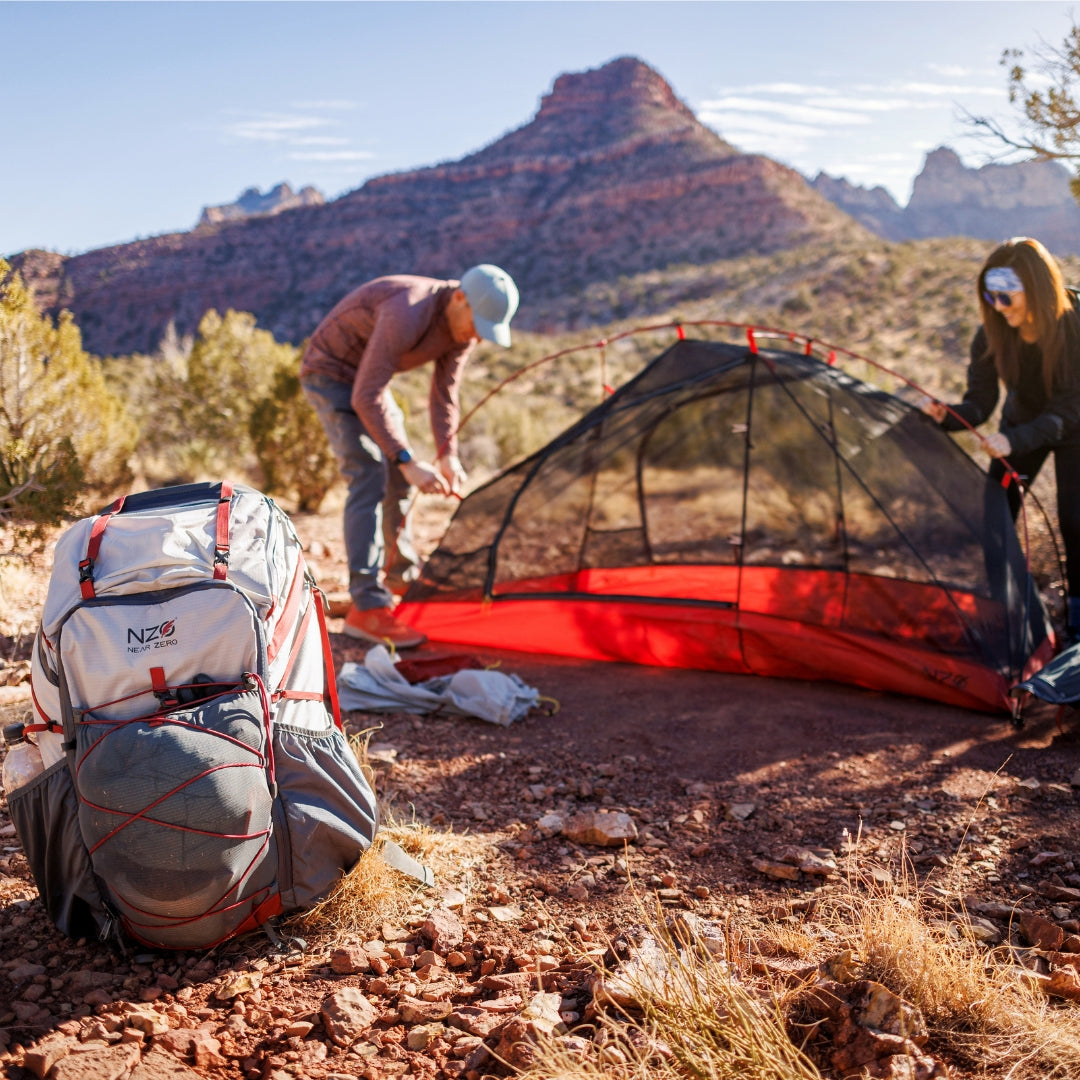 Near Zero Outdoor Gear - The Dean TR 50 Overnight Hiking Backpack - Backpack in foreground, while 2 people set up tent in background