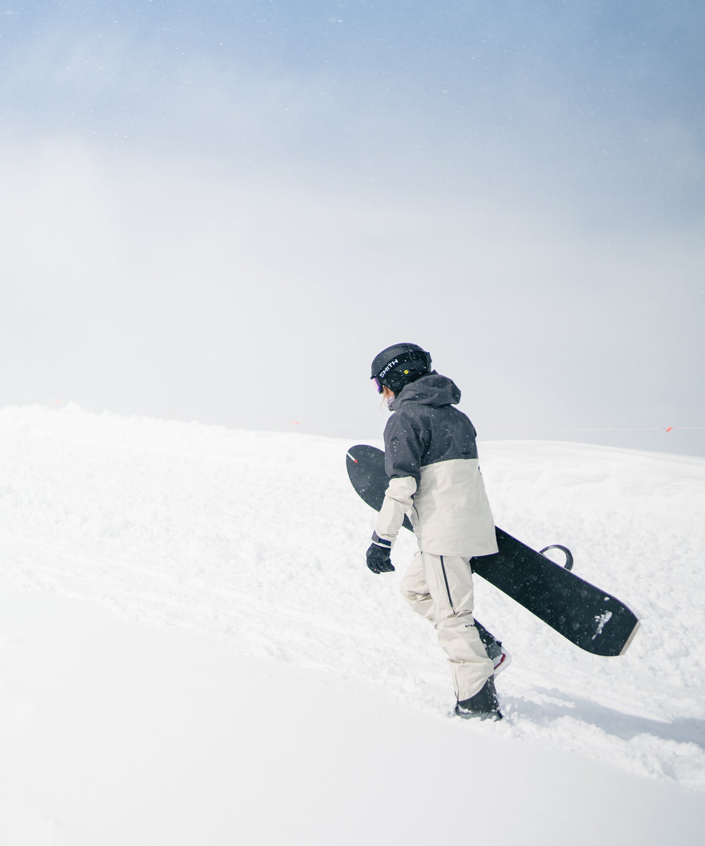 Strafe Outerwear - Meadow 3L Shell Jacket - Snowboarder wearing jacket, walking up a snowy slope - Light Khaki