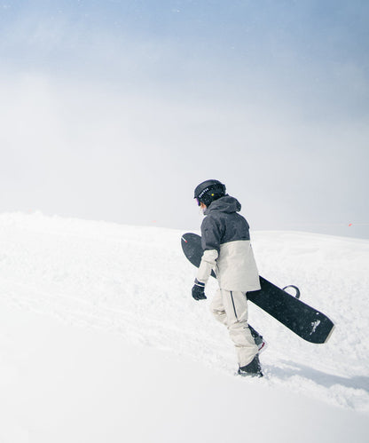 Strafe Outerwear - Meadow 3L Shell Jacket - Snowboarder wearing jacket, walking up a snowy slope - Light Khaki